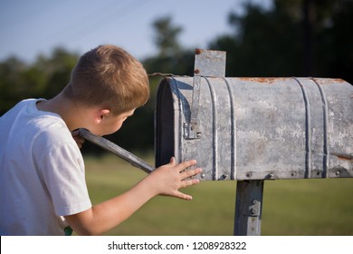 A Cute Boy, Checking The Mail In An Open Mail Box. The Kid Is Waiting For The Letter, Checks The Correspondence And Looks Into The Metal Mailbox.