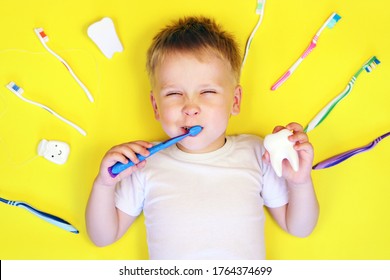 Cute Boy Child Kid Brushes His Teeth On Yellow Background. Teeth Cleaning, Oral Care, Dental Hygiene Concept 