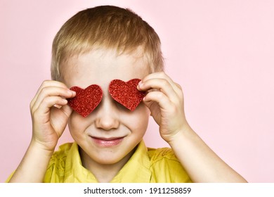 Junge, der seine Augen mit Herzen auf rosafarbenem Hintergrund bedeckt. Valentinstag.
Porträt eines Kindes. Konzept Urlaub Valentinstag, Mütter Tag, 8 März.