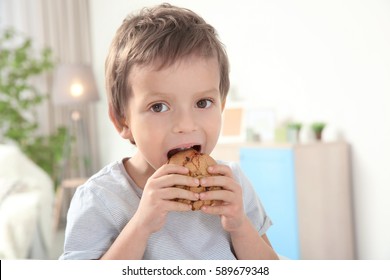 Cute boy eating cookie at home