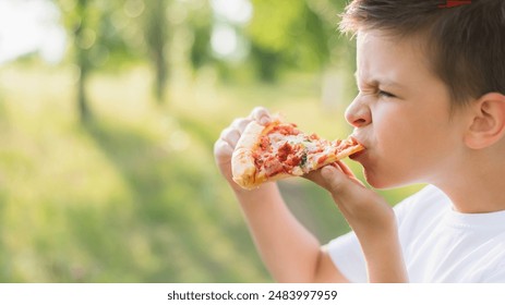 Cute boy eating pizza outdoors in summer - Powered by Shutterstock