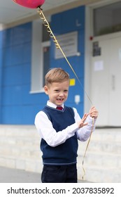 Cute Boy First Grader At School With A Balloon In His Hand On A Sunny Autumn Day. Celebration On September 1st. Knowledge Day. Selective Focus