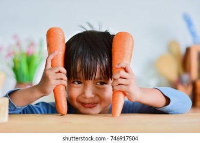 Cute Boy Holding A Carrot. And Make A Looks Crafty In The Kitchen.