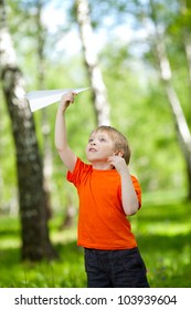 Cute Boy Holding A Paper Airplane In Park