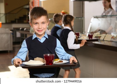 Cute boy holding tray with healthy food in school canteen - Powered by Shutterstock