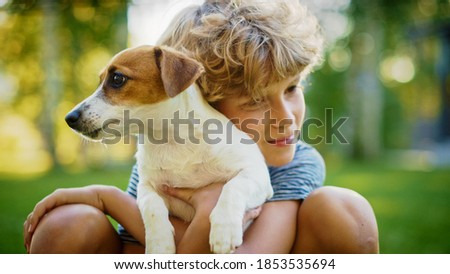Cute Boy Holds His Favourite Pedigree Dog Friend while Having Picnic Outdoors on the Lawn. He Pets and Cuddles His Little Smooth Fox Terrier. Idyllic Summer House.