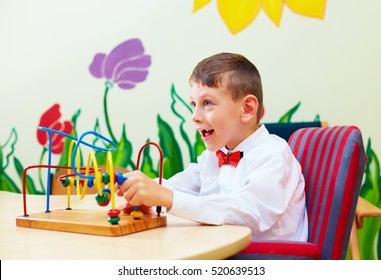 cute boy, kid in wheelchair solving logical puzzle in rehabilitation center for children with special needs