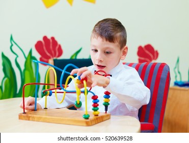 Cute Boy, Kid In Wheelchair Solving Logical Puzzle In Rehabilitation Center For Children With Special Needs