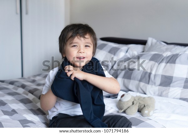 布の着方を習ったかわいい少年 ベッドに座った4歳の子どもが学校のジャンパーを着て 男の子が学校に着替え 子どもがベッドルームで着替える の写真素材 今すぐ編集