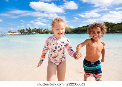 A Cute Boy And Little Girl Running And Splashing Together Holding Hands In The Caribbean Ocean While On A Family Vacation