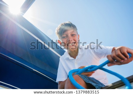 Cute boy on board of sailing yacht on summer cruise. Travel adventure, yachting with child on family vacation. Kid clothing in sailor style, nautical fashion.