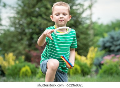 Cute boy playing a game throwing rings outdoors in summer Park