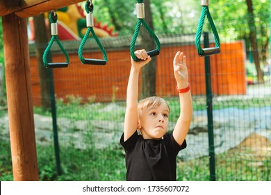 Cute boy playing on monkey bars. Kids sport outdoors. Summer vacation, camp and leisure. Street sports exercise. Sports, lifestyle and healthy childhood. Modern adventure park, playground. - Powered by Shutterstock