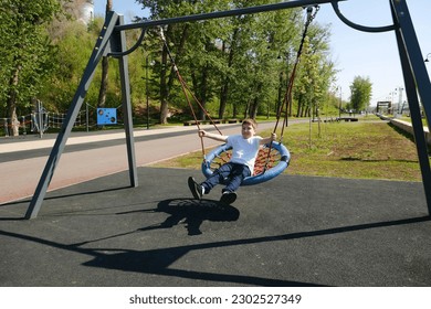 Cute boy rides on a swing on the embankment.