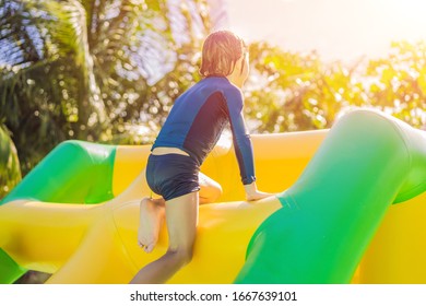 Cute Boy Runs An Inflatable Obstacle Course In The Pool