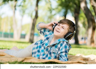 Cute boy of school age in park wearing headphones