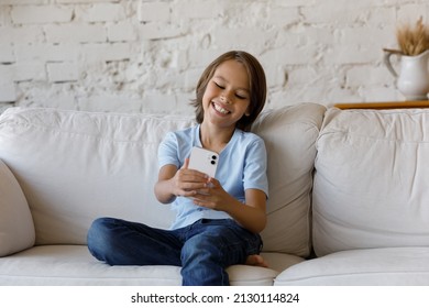 Cute Boy Sit On Sofa At Home Having Fun Using Smart Phone. Young Gen Z And Modern Technology Usage, Leisure On-line, Take Selfie Pictures, Make Video Call, Communication With Friend Remotely Concept