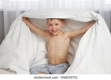 The Cute Boy Smiling Covered His Head With A White Blanket And Did Not Want To Go To Sleep In His Crib