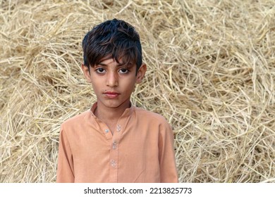 Cute Boy Smiling In Front Of Hay