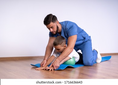 Cute Boy With Special Needs On The Mat Doing Exercises. Special Treatment In The Hospital