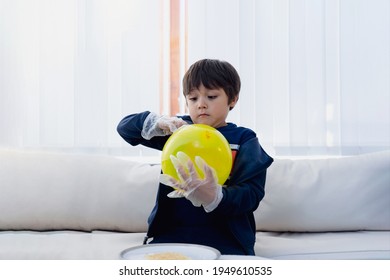 Cute Boy Wearing Disposable Protective Plastic Glove And Holding Yellow Balloon,Kid Preparing Science Project About Static Charged, Child Looking Curiously At Science Experiment,Home Schooling Concept