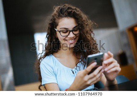 cute brazilian girl with curly hair writes her boyfriend on her cellphone