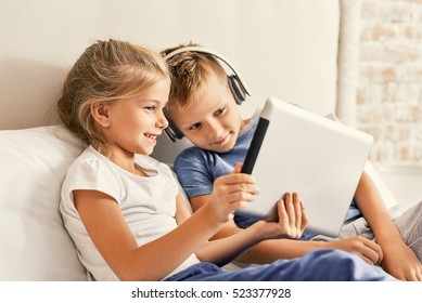 Cute brother and sister enjoying tablet at home