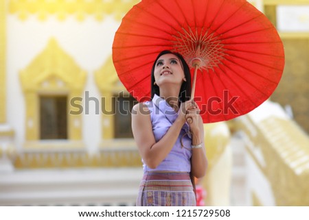 Cute Burmese women with traditional  Burma dress holding red umbrella walk in temple 