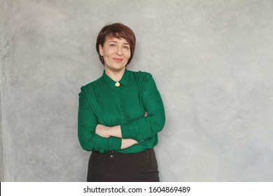 Cute Business Woman Wearing Green Shirt On Gray Stucco Background, Portrait