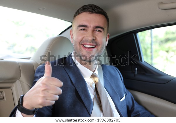 Cute\
businessman in backseat giving a thumbs\
up