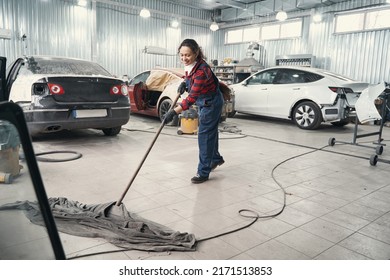 Cute car mechanic wiping floor with mop - Powered by Shutterstock