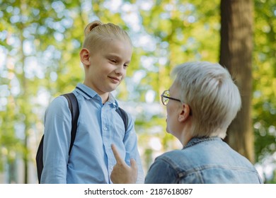 Cute Caucasian Blonde Boy With Ponytail Going To School. Mother Having A Conversation With Child, Saying Goodbye And Givng Advice. Back To School Concept