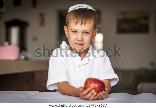 伝統的なユダヤ人の白いキッパ帽を被り 手にリンゴを持つ かわいい白人の青い目の少年 ユダヤ人の新年を祝うロシアのユダヤ人の少年 ロシュ ハシャナ の写真素材 今すぐ編集