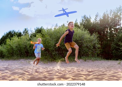 Cute Caucasian Boys Running Along Beach Going Launching A Toy Plane. High Quality Photo