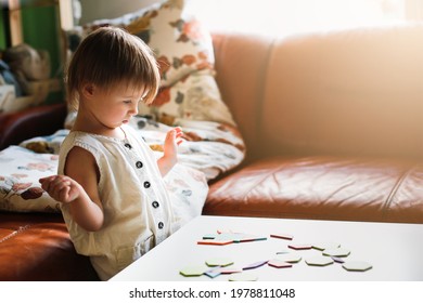Cute caucasian child toddler playing with a wooden mosaic on the table, earlier child development and children's games, kid playing with a puzzle close-up, toning