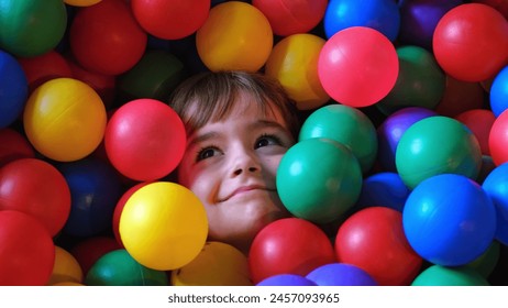 Cute Caucasian Girl Kid Buried under Colored Plastic Balls in Play Arena Pool - Powered by Shutterstock