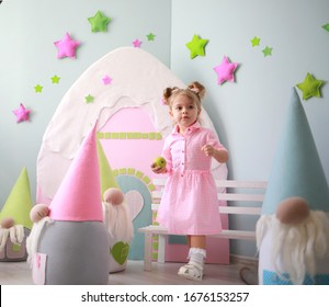 Cute Caucasian Girl With Ponytails Having Fun In A Crowd Of Large Toy Gnomes In Her Bright Room