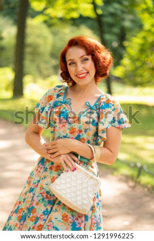 cute caucasian girl with red bob haircut in retro dress enjoying life in city Park in summer sunny day