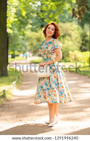 cute caucasian girl with red bob haircut in retro dress enjoying life in city Park in summer sunny day