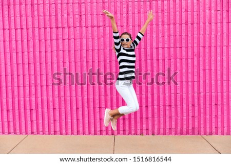 Cute caucasian girls celebrating her 13th birthday becoming a teenager in front of a hot pink wall outside by jumping up with joy