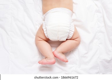 Cute caucasian infant baby in white nappy on light grey blanket. Top view. Banner format. Copy space. Diaper change and care of baby's skin. 