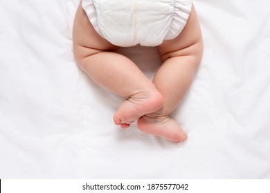 Cute caucasian infant baby in white nappy on light grey blanket. Top view. Banner format. Copy space. Diaper change and care of baby's skin. 