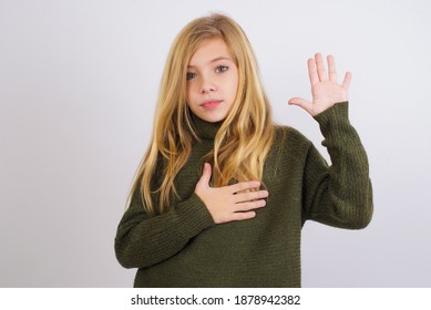 Cute Caucasian Kid Girl Wearing Green Knitted Sweater Against White Wall Swearing With Hand On Chest And Open Palm, Making A Loyalty Promise Oath