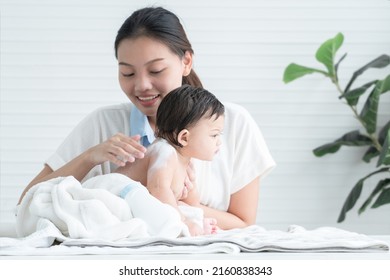 Cute Caucasian Little Naked Toddler Baby Girl Sitting On Towel After Bathing And Wipe Body Dry While Young Asian Mother Apply Talcum Powder On Her Kid Skin At Home. Hygiene Care For Children Concept