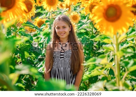 Cute Caucasian teen girl smiling in a field of sunflowers. Summer time concept.