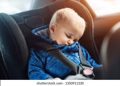 Cute Caucasian Toddler Boy Sleeping In Child Safety Seat In Car During Road Trip. Adorable Baby Dreaming Asleep In Comfortable Chair During Journey In Vehicle. Children Care And Safety On Roads