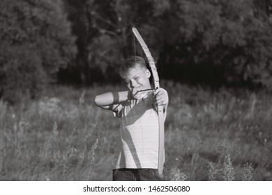 Cute Caucasian Young Child Playing Wooden Toy Bow And Arrow Outside. Setting Goals Concept. Horizontal Black And White Photography.