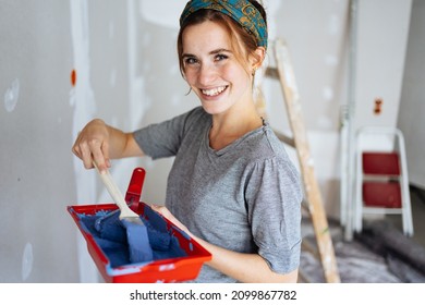 Cute charismatic young woman mixing blue paint as she decorates the walls of her new home or does renovations - Shutterstock ID 2099867782