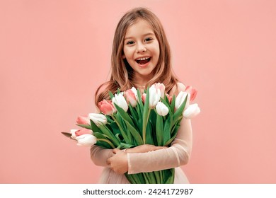 Cute charming little girl in a pink dress holds a bouquet of tulips flowers isolated on a pink background. - Powered by Shutterstock