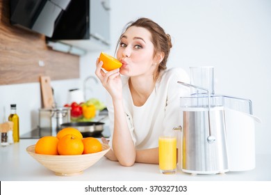 Cute Charming Young Woman Making Juice And Eating Oranges On The Kitchen